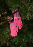 Pink gloves with 'HOPE' and 'LOVE' text on a pine branch