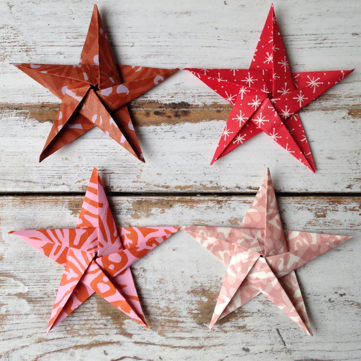 Four patterned paper stars on a wooden surface