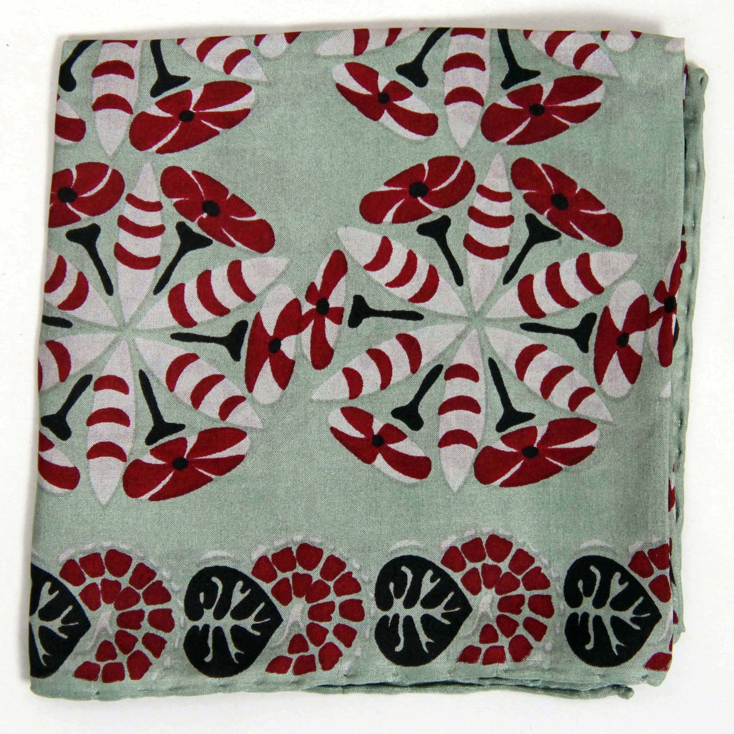 Folded fabric with red, black, and white floral pattern on a light green background