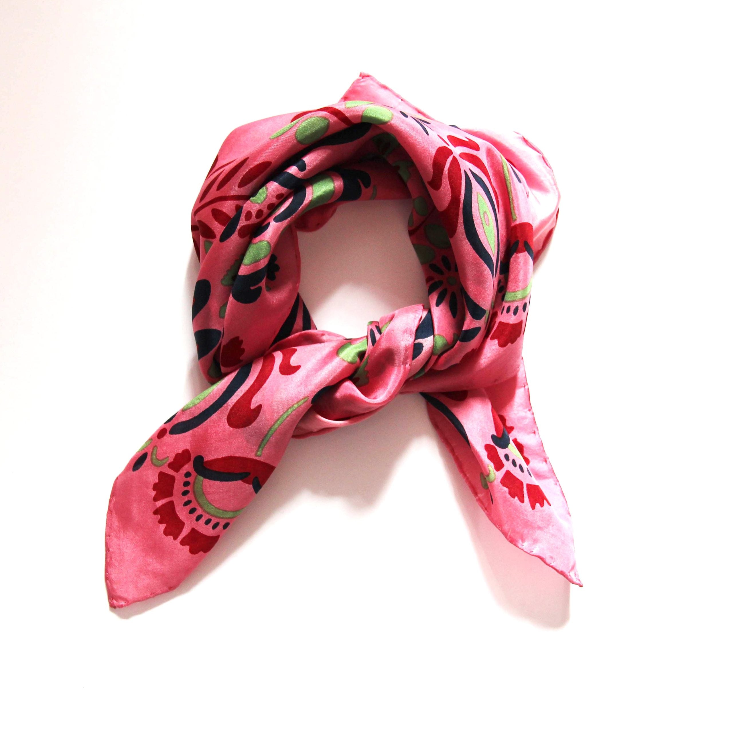 Pink scarf with black and green floral pattern on a white background
