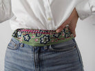 Person wearing a white shirt and blue jeans with a floral belt.