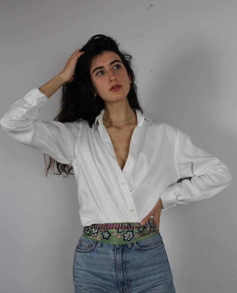 Woman wearing a white shirt and blue jeans against a plain background