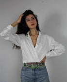 Woman wearing a white shirt and blue jeans against a plain background