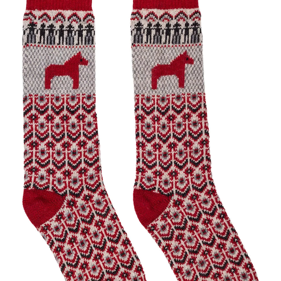 A pair of crew socks with a red, gray, and black Nordic/Fair Isle pattern, featuring a red Dala horse motif and a red ribbed cuff, shown against a plain white background.