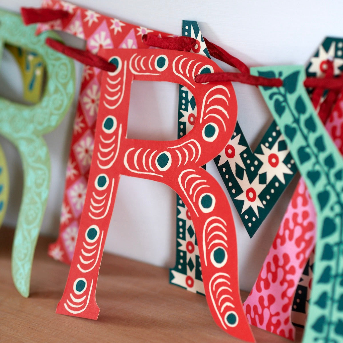 Colorful paper letter 'R' with decorative patterns on a wooden surface.