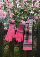 Pair of pink gloves with 'LOVE' and 'HOPE' text, and a patterned scarf against a floral background.