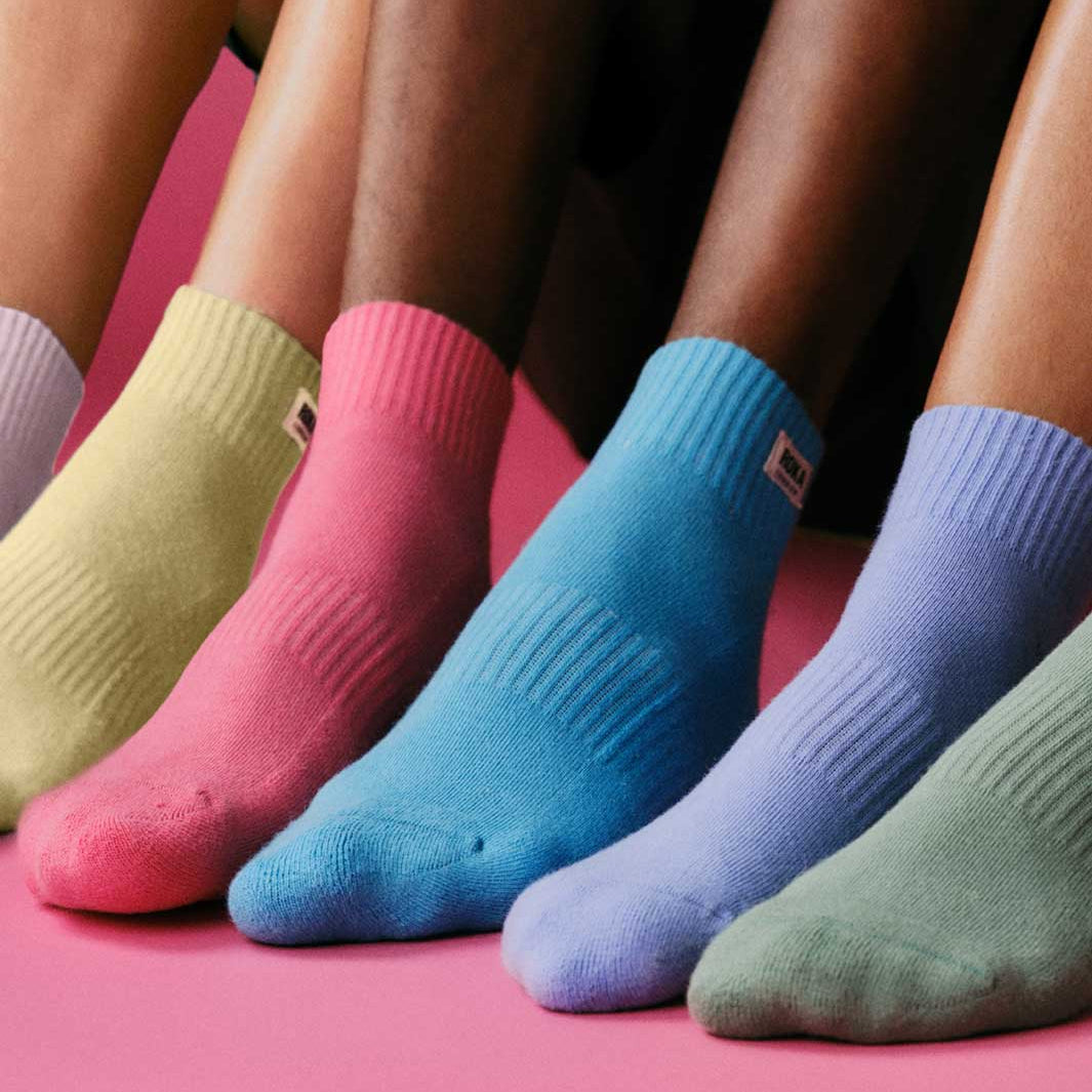 Five pairs of colorful socks on a pink background