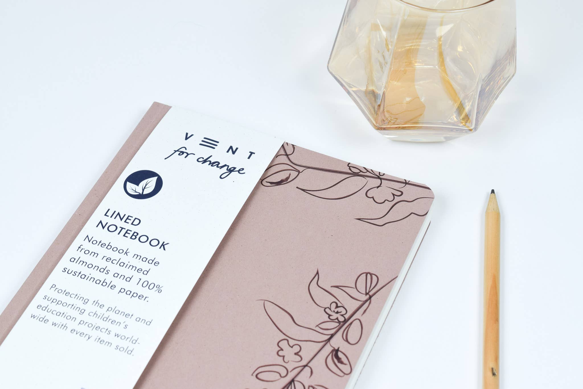 Notebook with 'Vent for Change' label on a white surface with a pencil and candle.