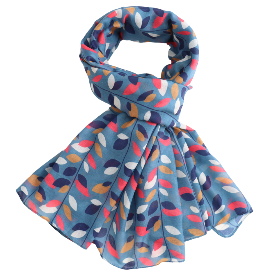 A lightweight scarf with a blue base and an allover abstract leaf pattern in navy, coral pink, mustard yellow, and white, styled in a loop on a plain white background.