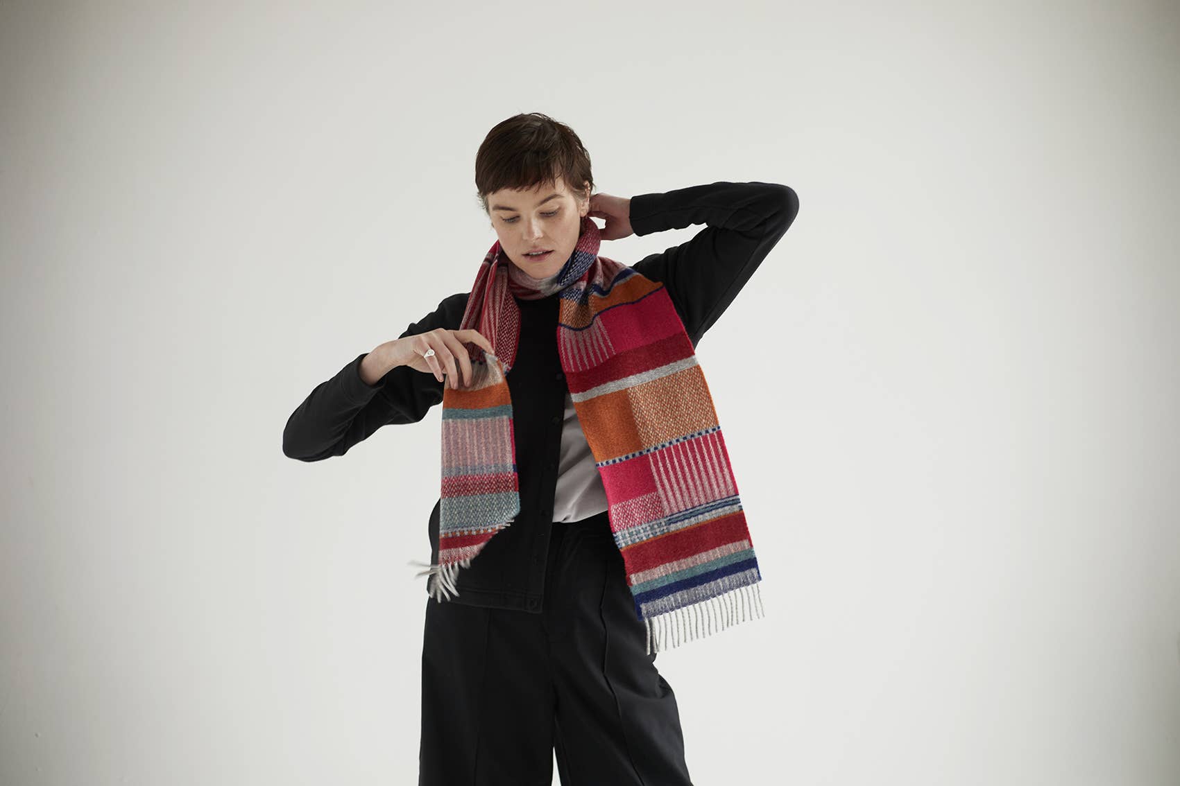 Person wearing a colorful striped scarf against a plain background