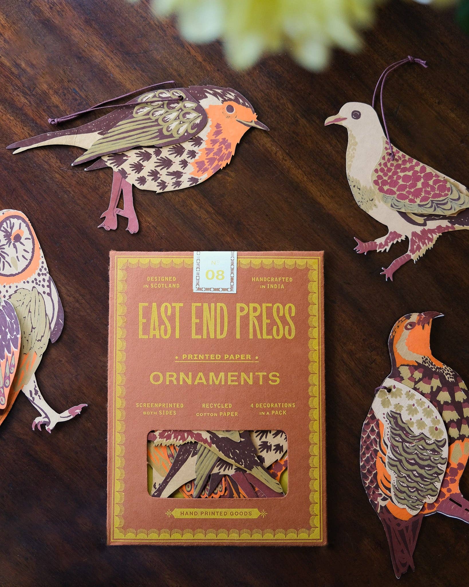 Box of East End Press ornaments with decorative bird ornaments on a wooden surface