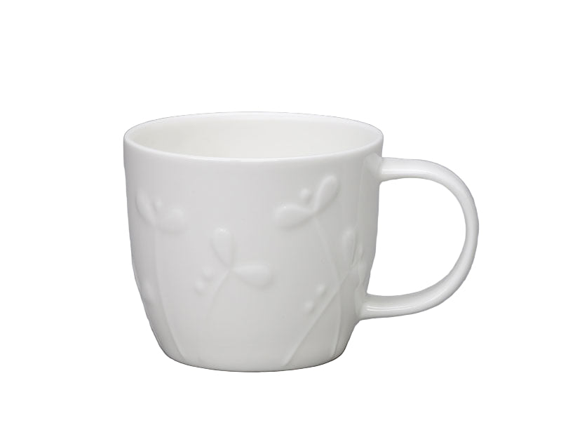 White ceramic mug with embossed design on a gray background