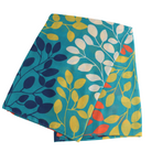 A folded square textile, likely a scarf or pocket square, featuring a botanical leaf pattern in teal, navy, yellow, white, and coral red on a white background.