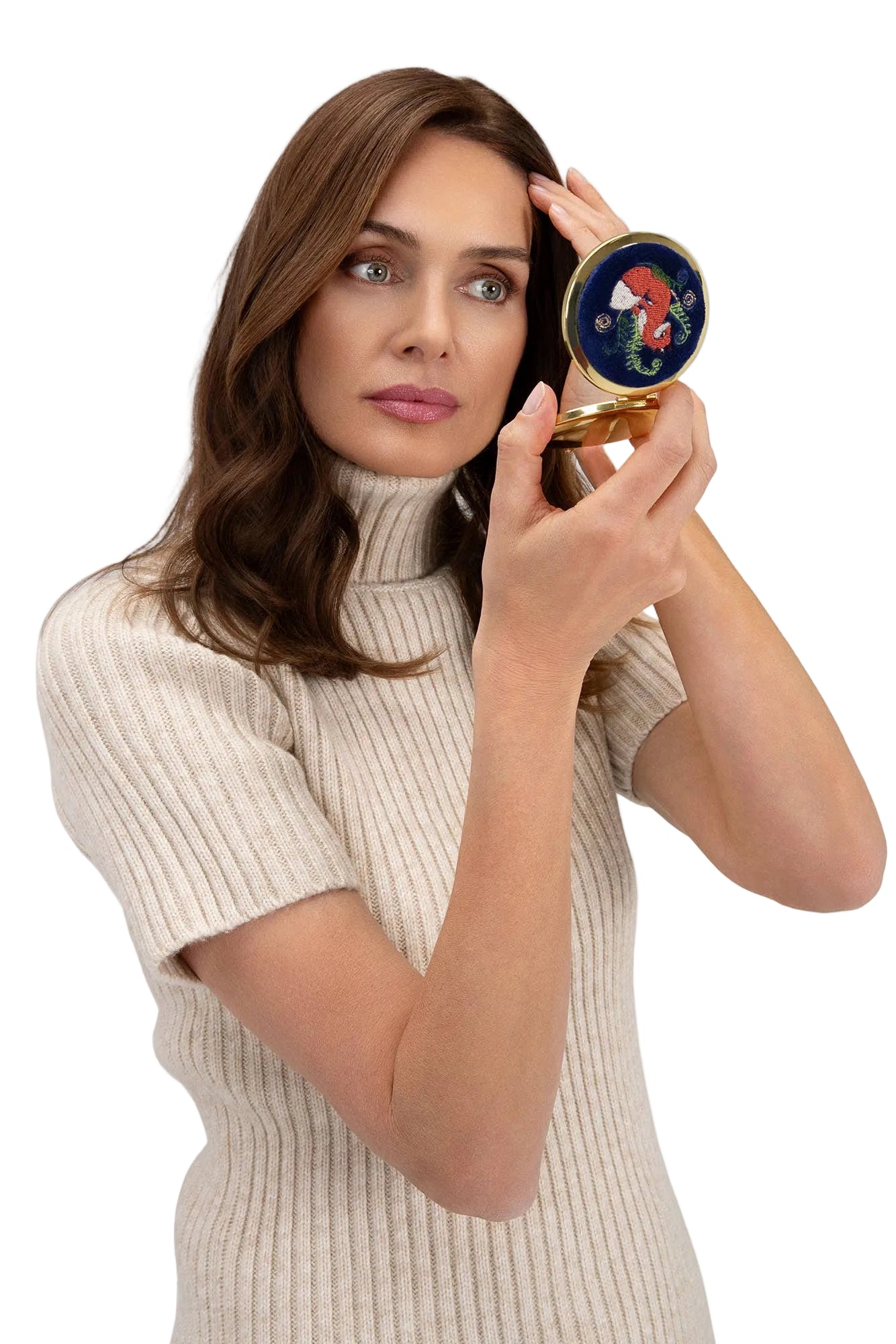 Woman holding a compact mirror with a decorative case on a white background
