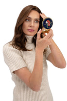 Woman holding a compact mirror with a decorative case on a white background