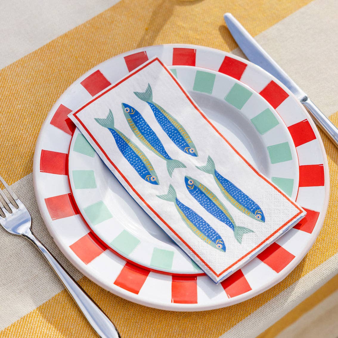 Decorative plate with fish design on a yellow tablecloth