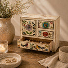 Decorative jewelry box with floral and bird designs on a wooden surface.