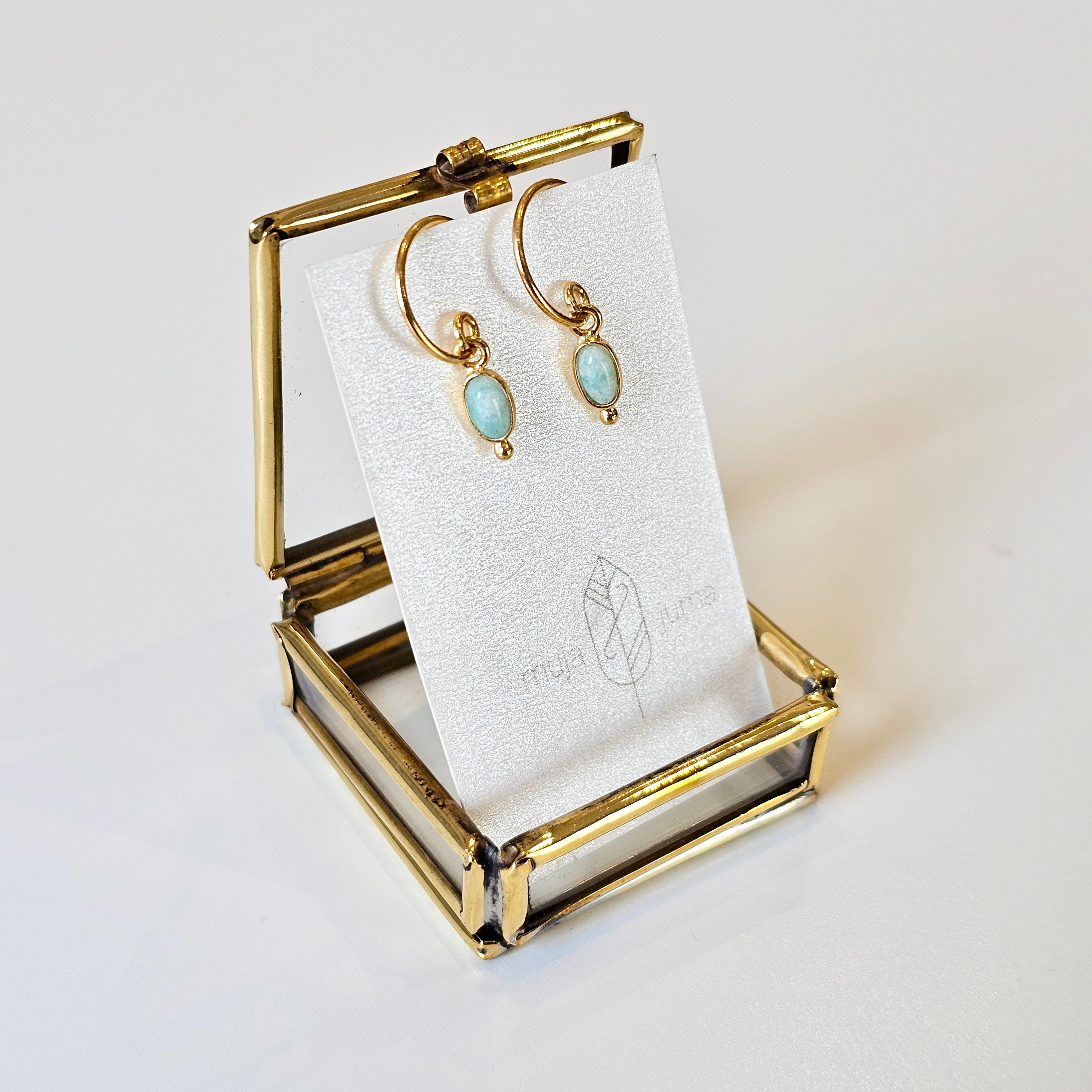 Gold earring holder with earrings on a white card against a light background