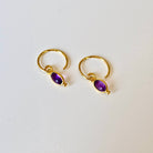 Gold hoop earrings with amethyst gemstones on a white background