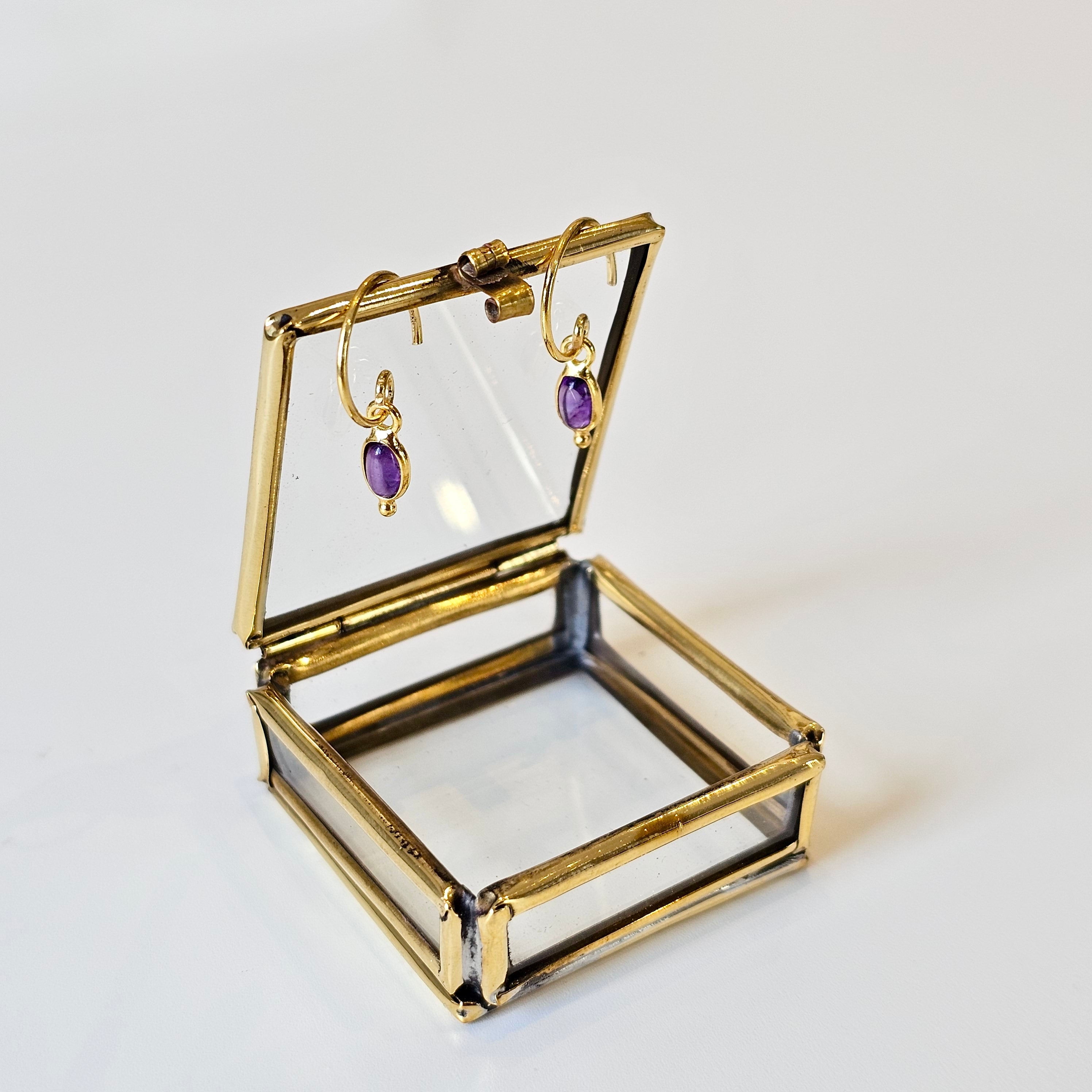 Gold jewellery box with amethyst earrings on a white background
