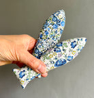 Hand holding a floral-patterned fabric sachet against a plain background