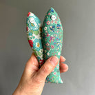 Two colourful fabric sachets held in a hand against a plain background