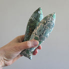 Hand holding two floral-patterned fish against a plain background