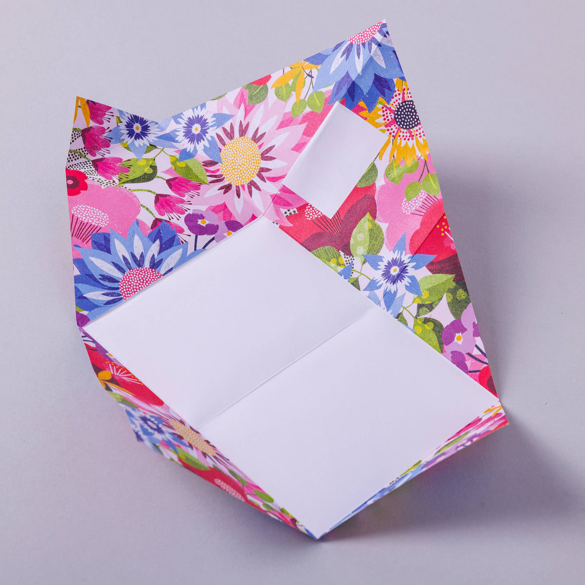 Colourful floral-patterned letter paper with a white interior on a grey background