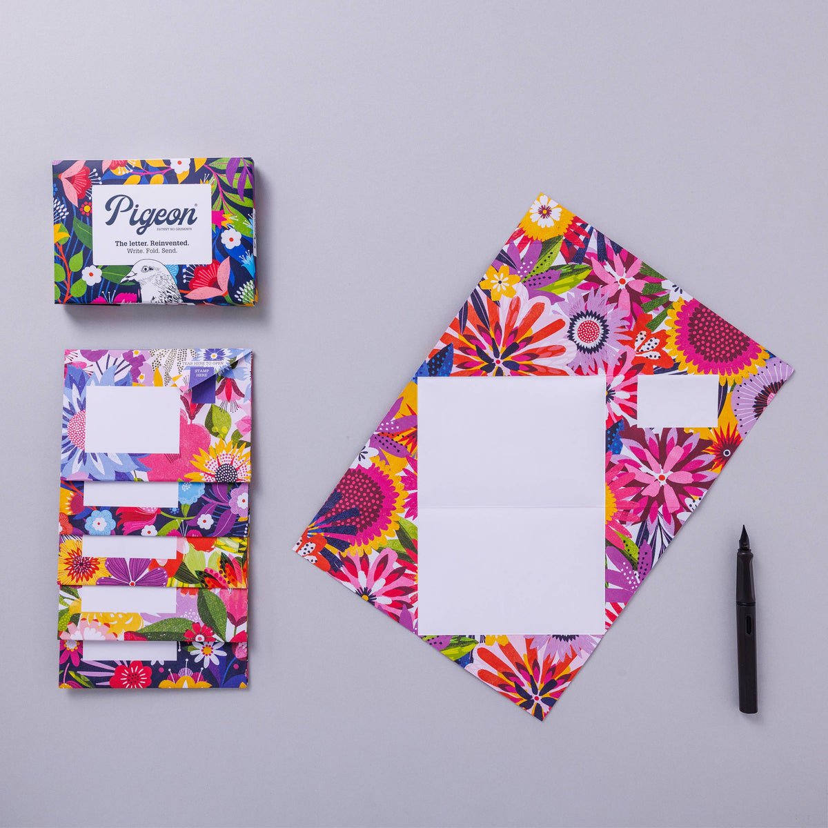 Colourful floral stationery set with a pen on a grey background