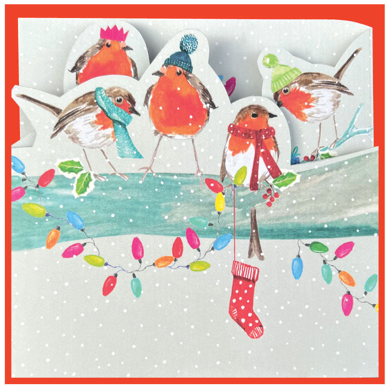 Illustration of robins wearing winter hats and scarves with Christmas lights on a snowy background.
