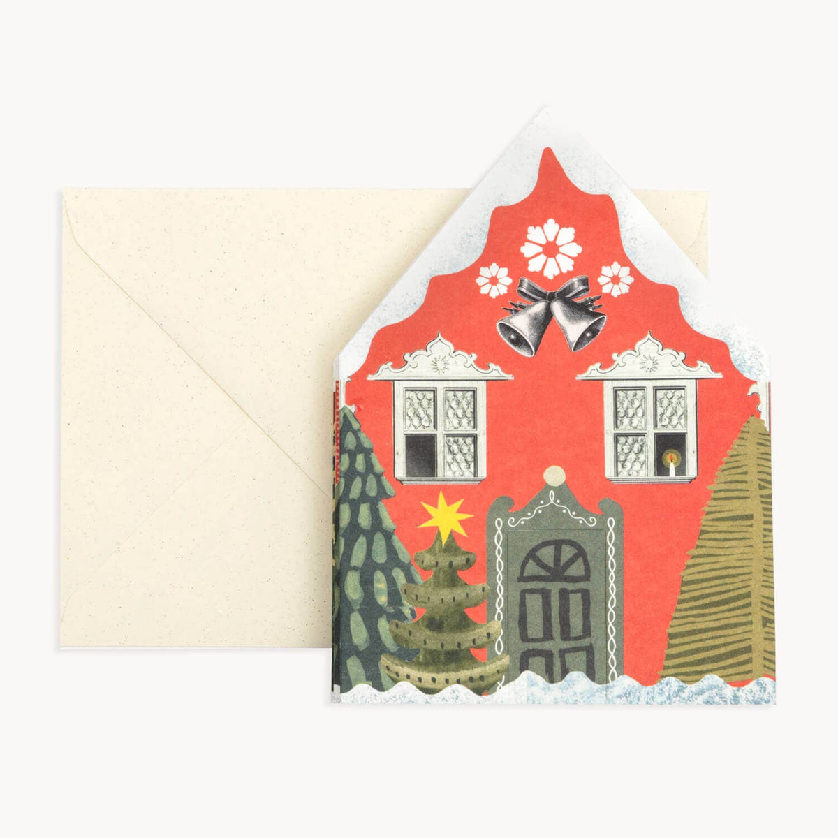 A Christmas-themed house-shaped greeting card with a red facade, bell details, snowflakes, and a decorated tree, shown with a cream envelope on a light gray background.
