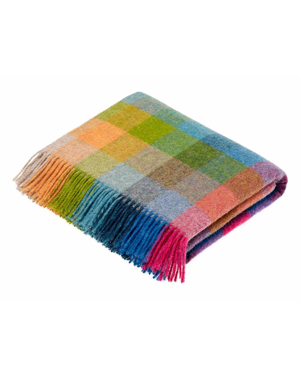 Multicoloured checkered blanket with fringes on a white background