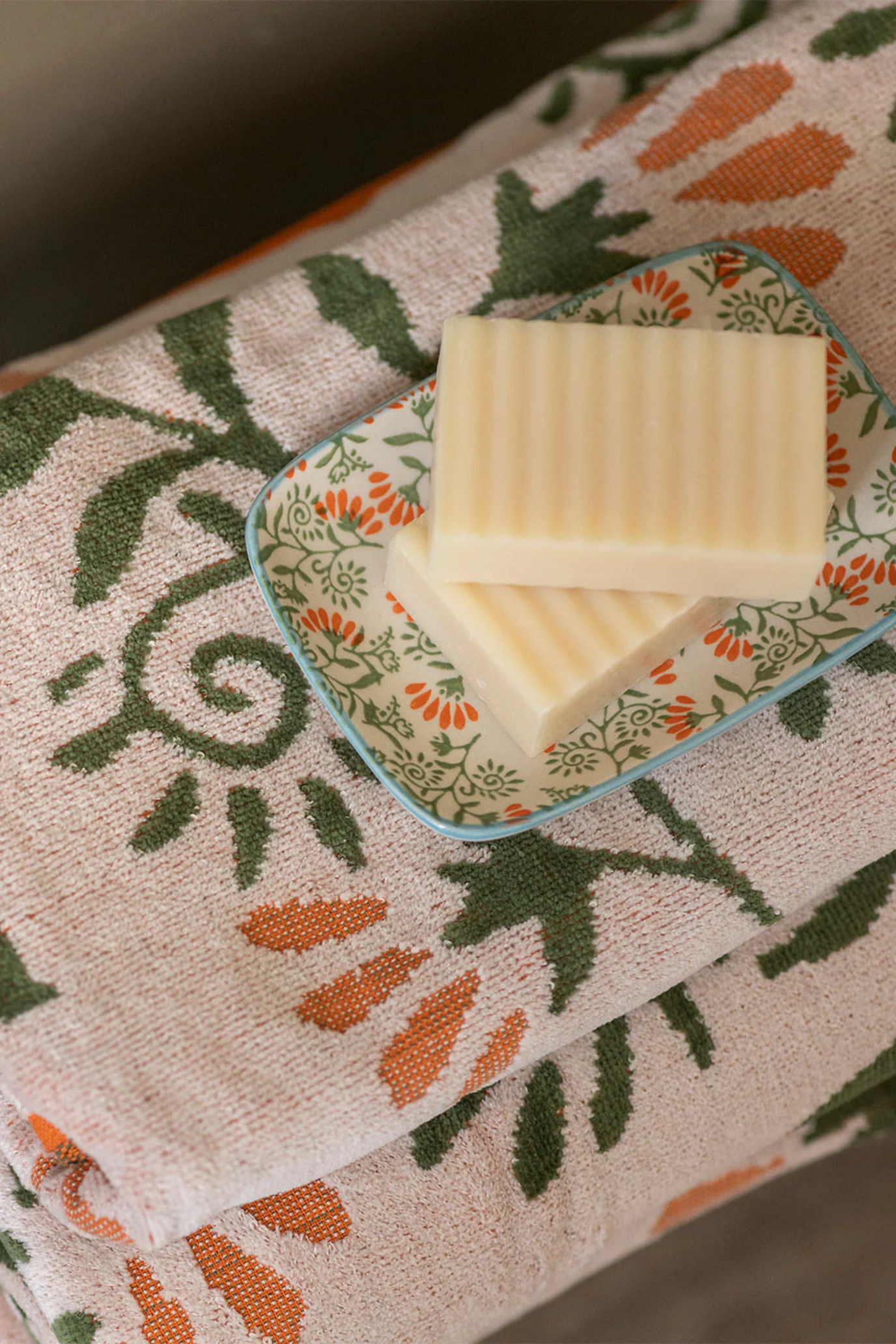 Two bars of soap on a decorative soap dish on a patterned towel