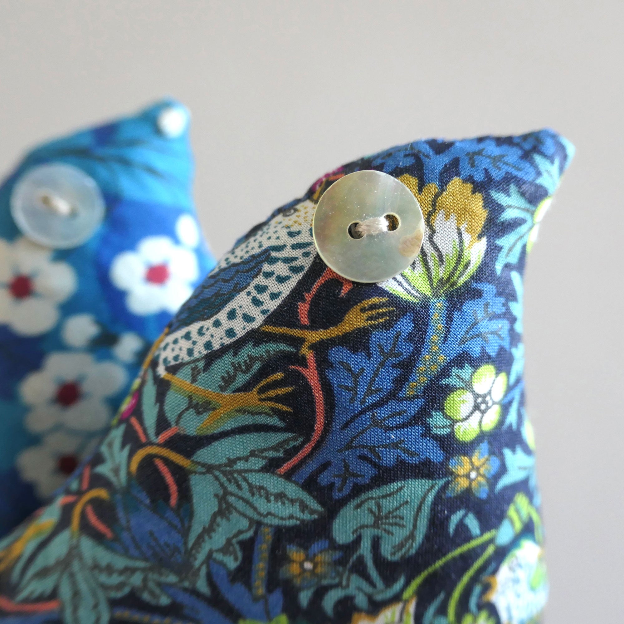 Decorative bird shaped lavender sachet with floral pattern and button eye on a neutral background