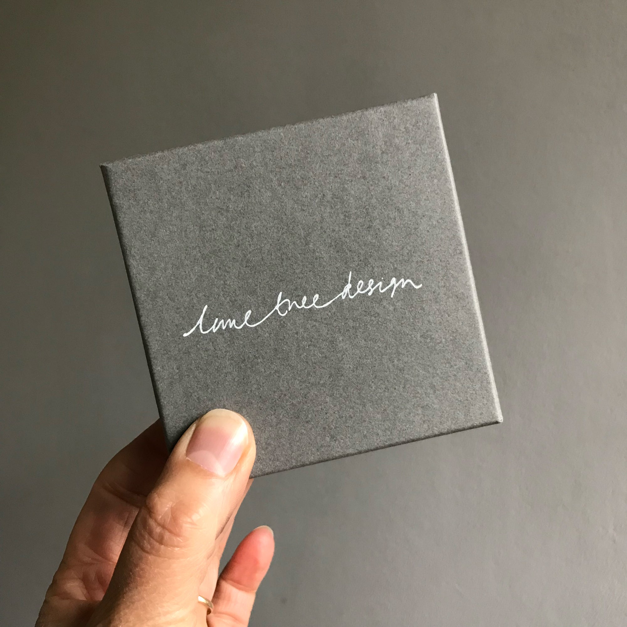 Single hanky box in grey held in a hand
