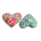 Two heart-shaped lavender sachets with red and green floral patterns on a white background