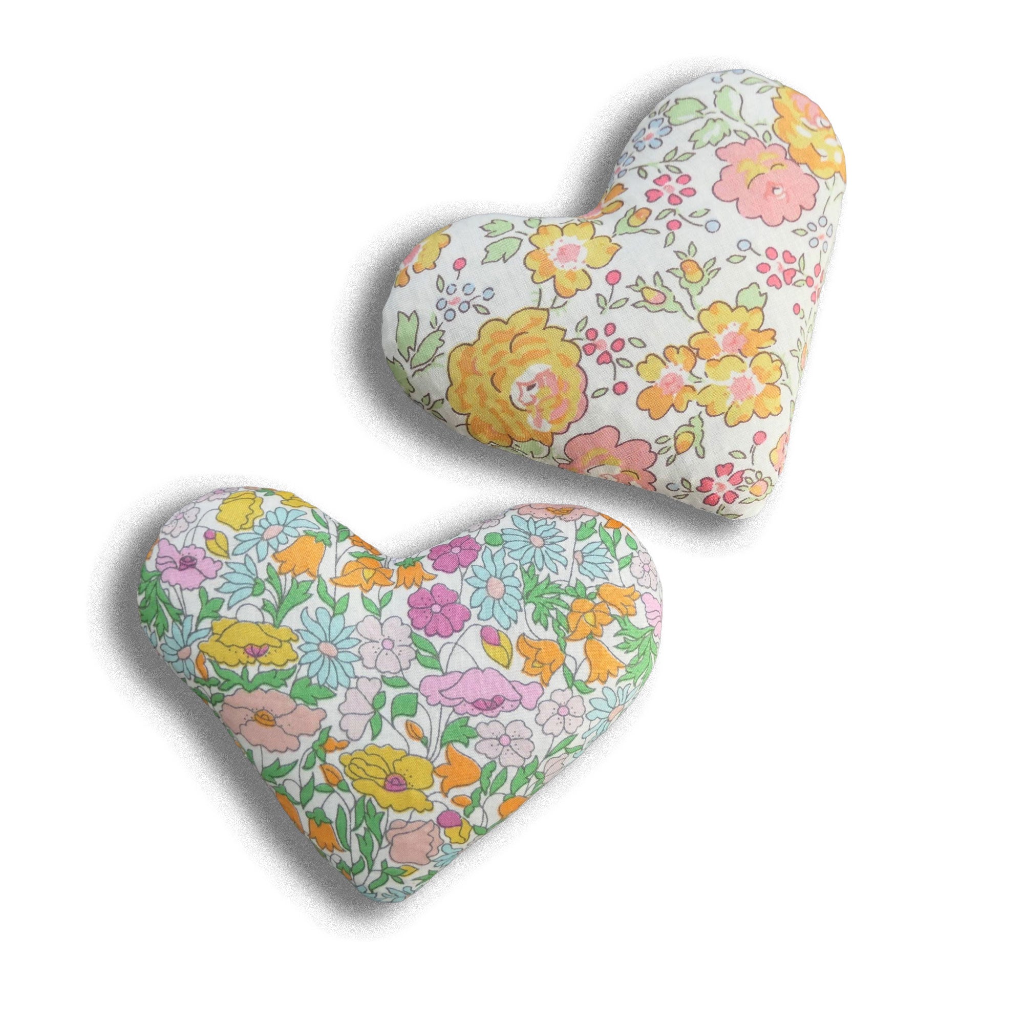 Two heart-shaped pillows with orange and yellow floral patterns on a white background