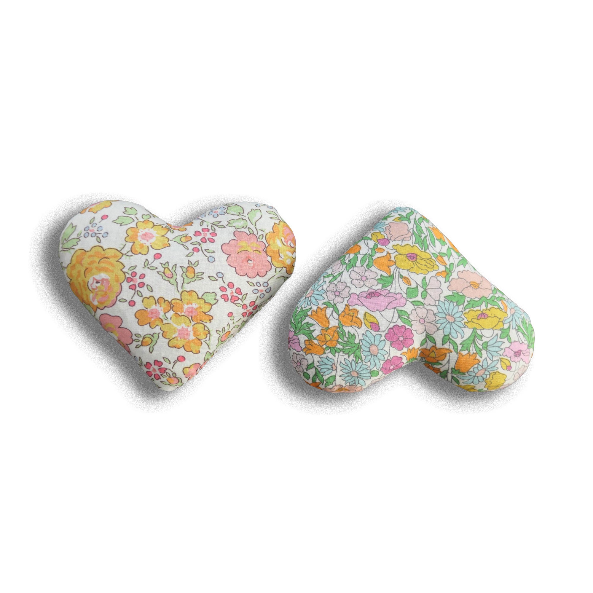 Two heart-shaped pillows with floral patterns on a white background