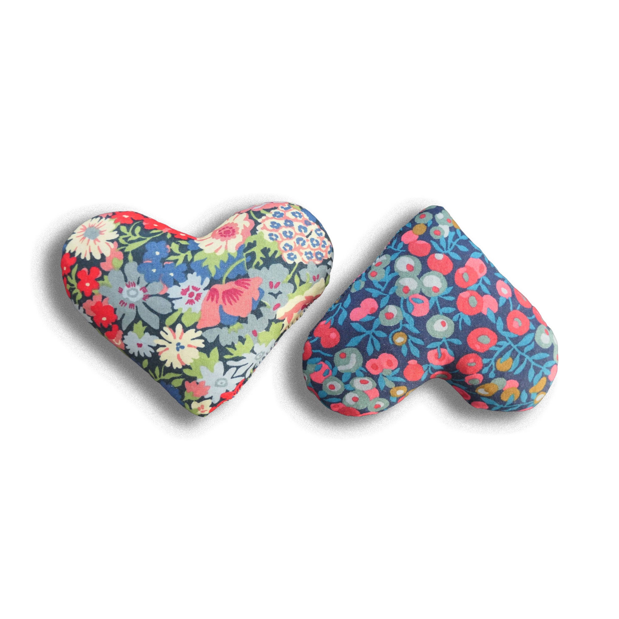 Two heart-shaped floral cushions on a white background