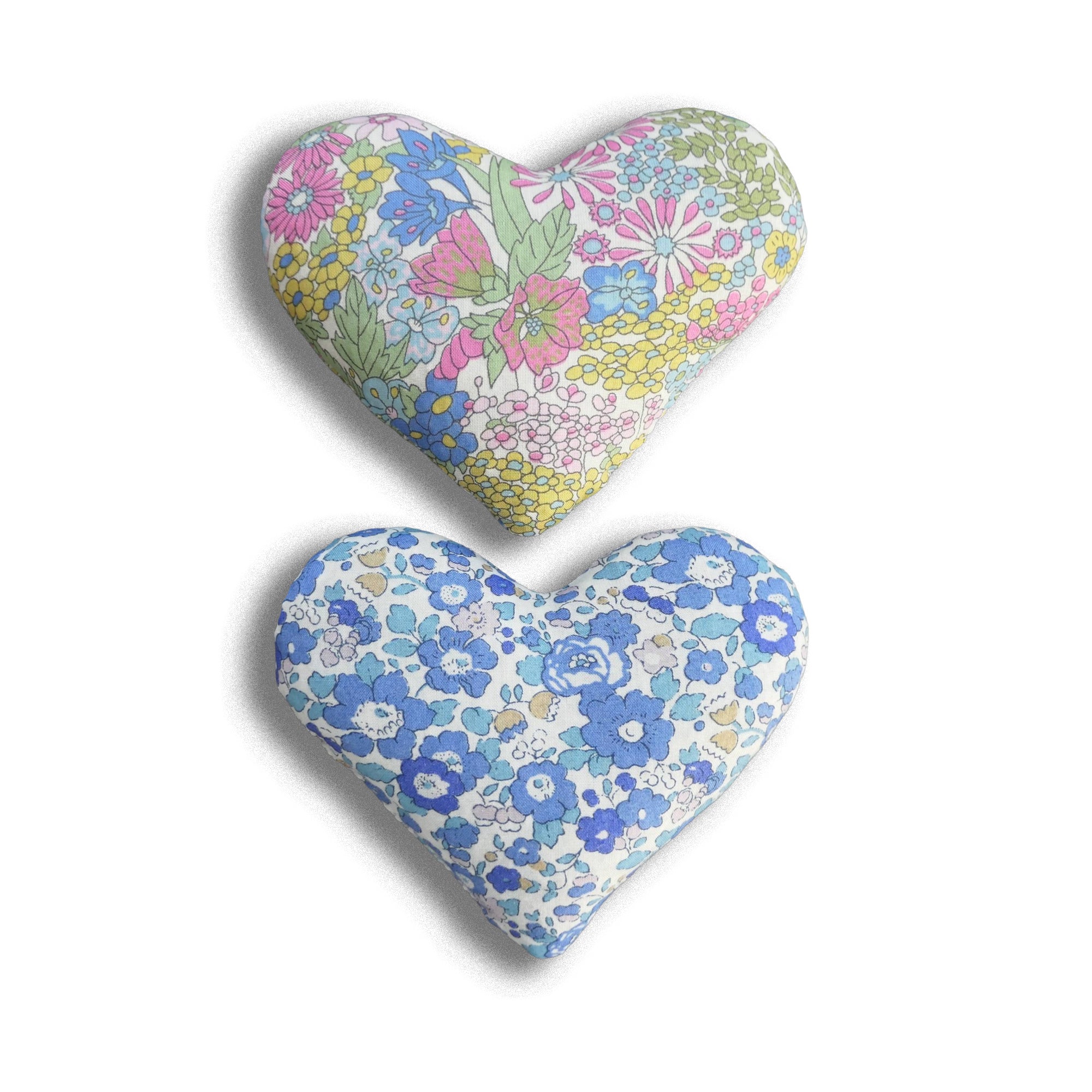 Two heart-shaped pillows with floral patterns on a white background