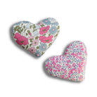 Two pink fabric hearts with floral patterns on a white background