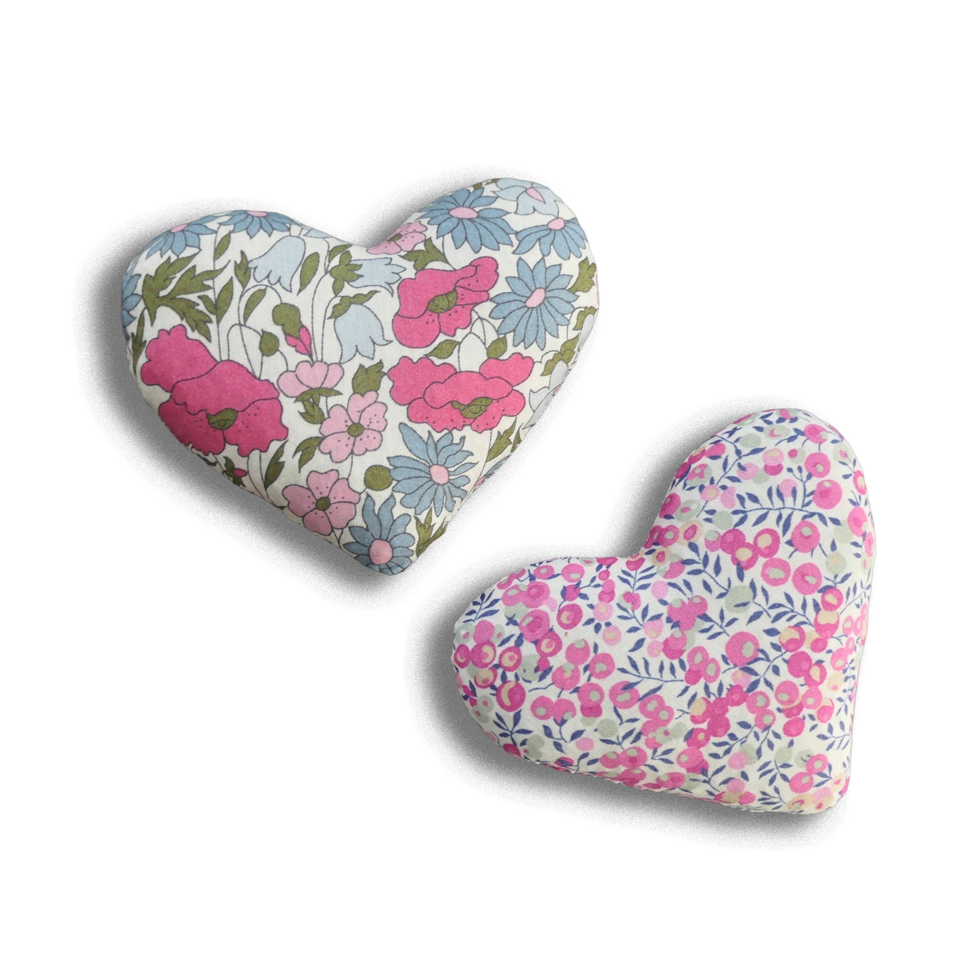 Two pink fabric hearts with floral patterns on a white background