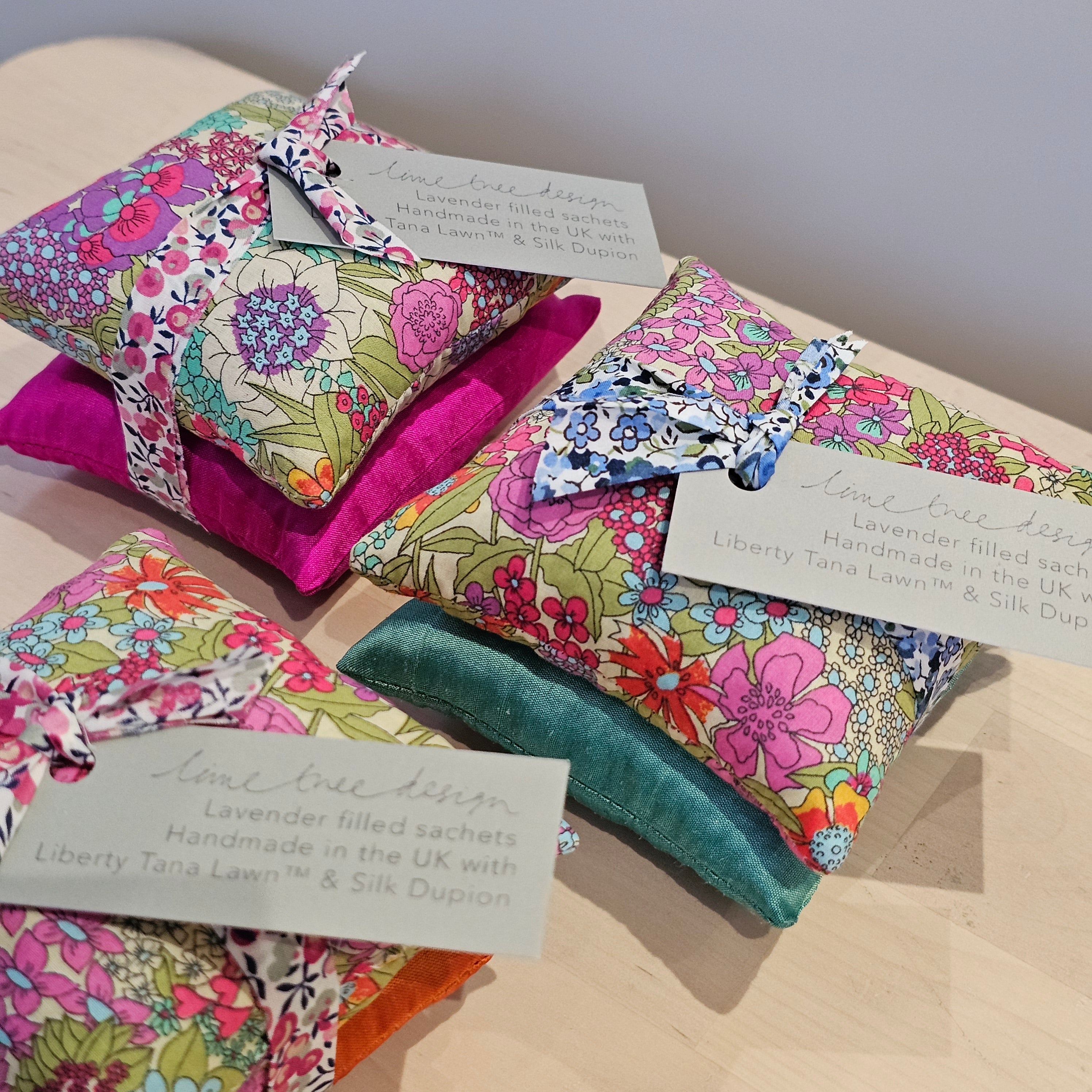 Colourful floral-patterned fabric sachets on a wooden surface with tags.