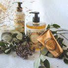 Three bottles of French skincare products with pump dispensers on a white surface with green leaves and flowers.