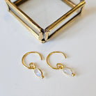 Gold hoop earrings with moonstone drops on a white surface