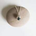Necklace with a green bead pendant on a stone surface