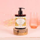 Hand soap bottle with floral label on a wooden block against a pink background