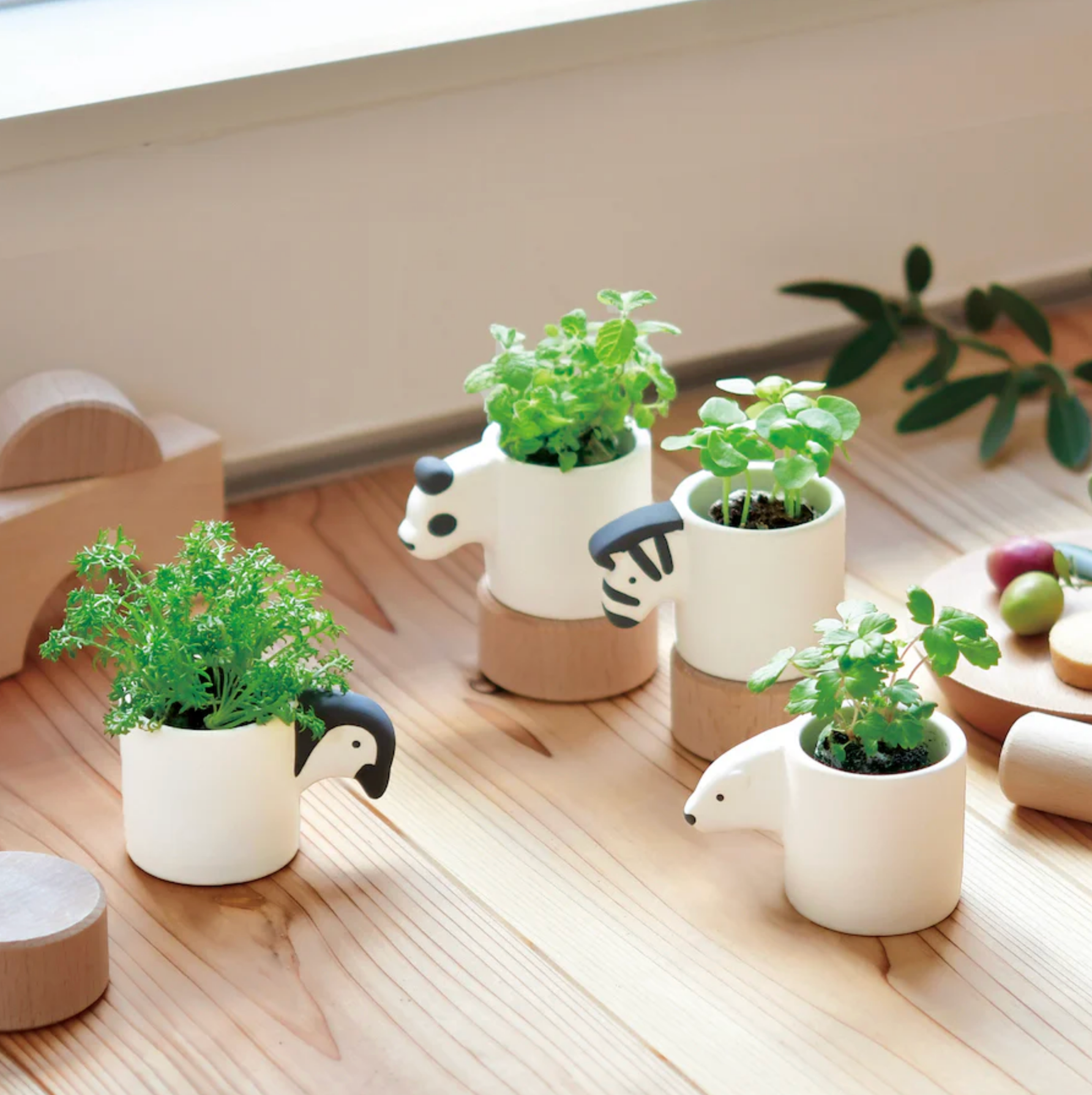 Set of small potted plants in animal-shaped pots on a wooden surface.