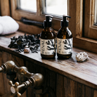 Two glass hand wash bottles sitting on a deep wooden windowsill