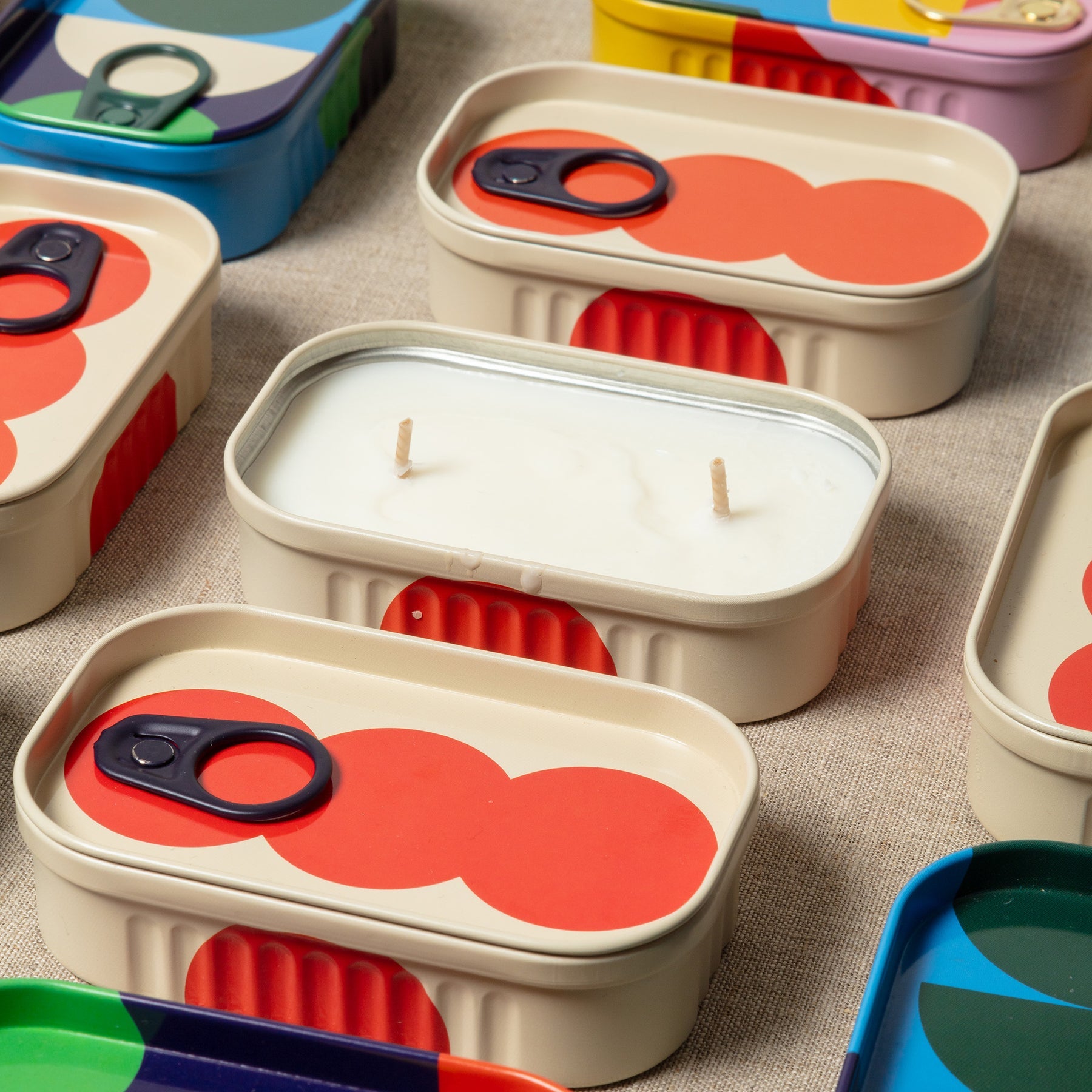 Set of colorful containers with red circular designs on a textured surface